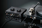 Pro-Ject Tube Box S3 B phono preamp with vacuum tubes, compact black design, featuring input and output connections for audio enhancement.