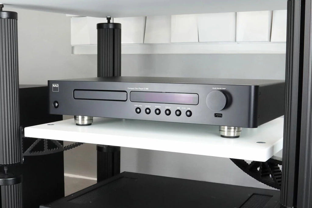 IsoAcoustics Orea Indigo speaker stands on a modern living room floor, showcasing their sleek design and sturdy build.